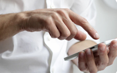 A close up of a person's hands holding and using a smartphone.