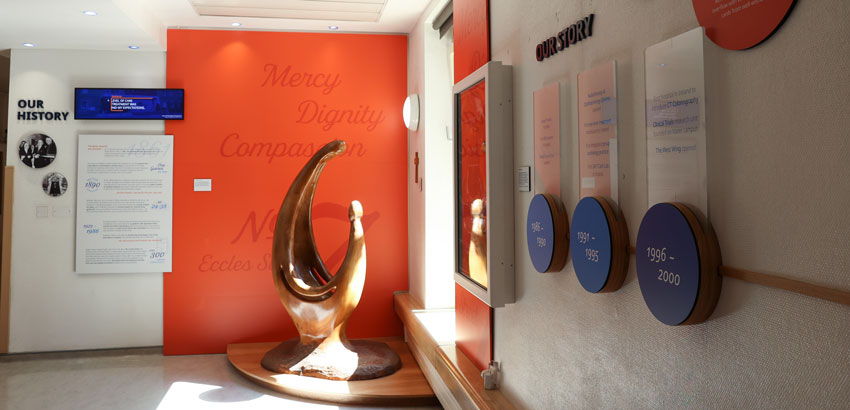 An interior hospital hallway in Mater Private Network in Dublin which has a large ornament and a storyboard on the walls.