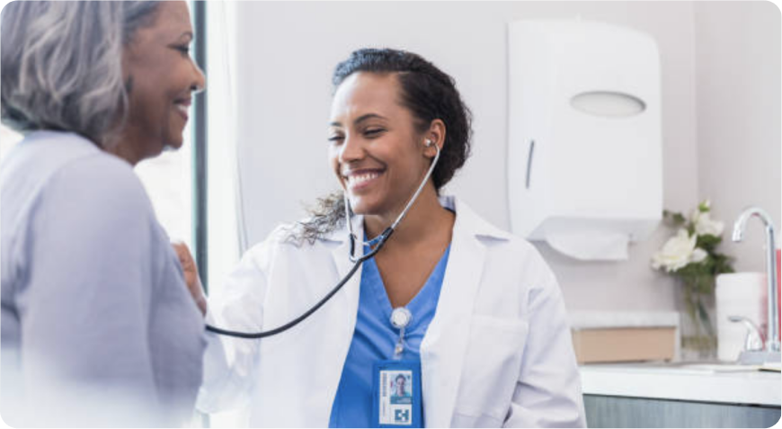 A female medical professional is using a stethoscope to listen to a female patient's chest.