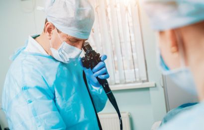 A male doctor looking into an endoscopy camera.