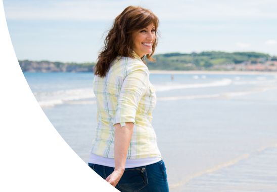 A smiling woman walking on a beach.