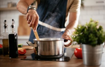A man stirring a steaming pot in a kitchen.