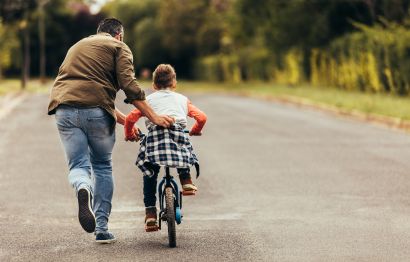 A father teaching his son how to ride a bike.
