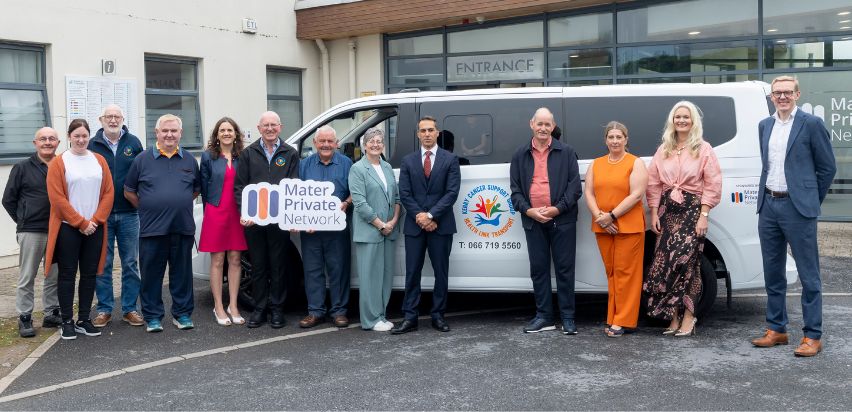A group of people posing beside the Kerry Cancer Bus in front of the Mid-Western Radiation Oncology Centre in Limerick.