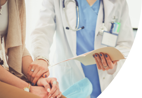 A doctor is holding a paper file while reaching to touch the arm of a patient.