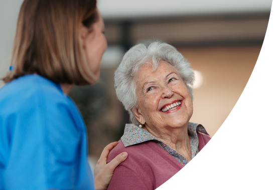 Smiling nurse talking with an older woman during a friendly conversation.